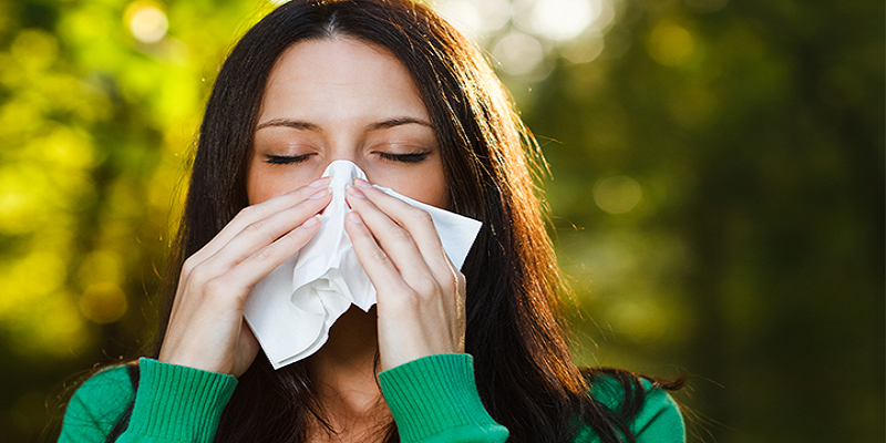 woman sneezing into tissue