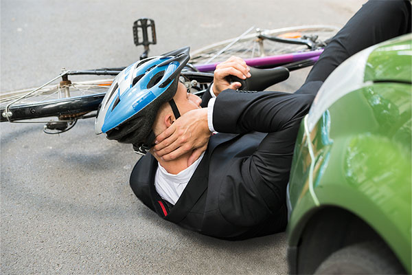 Bicyclist on the ground with injuries in front of a car after getting struck by the car in Oakland CA